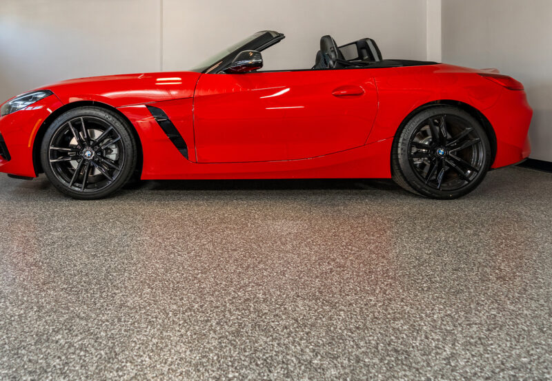 Red sports car parked in a garage with polyurea concrete floor coat.